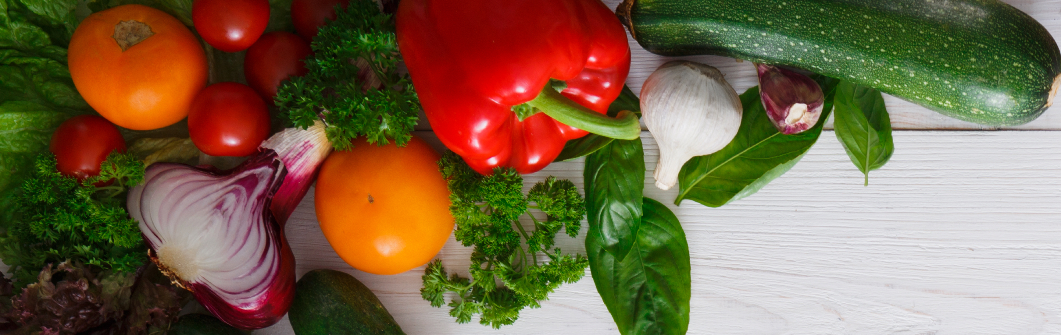 Arrangement of vegetables on a white wooden background.